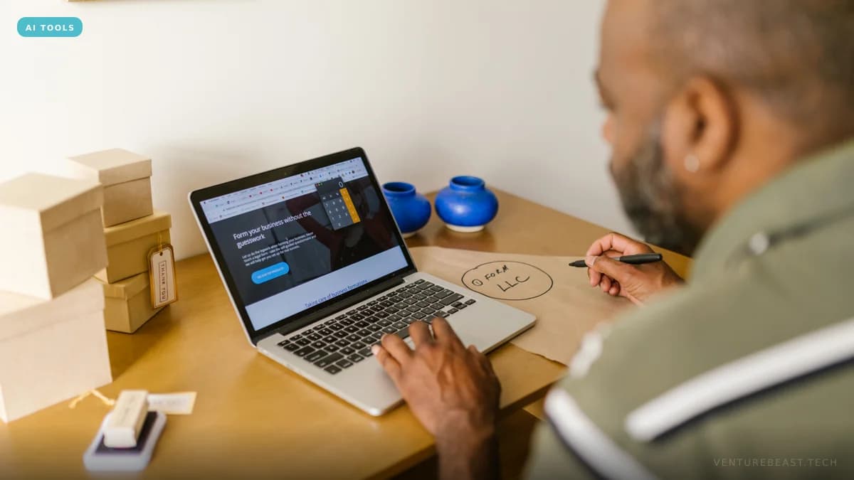 Small business owner typing on a laptop at a wooden desk beside stacked kraft gift boxes, sketching a plan on brown paper