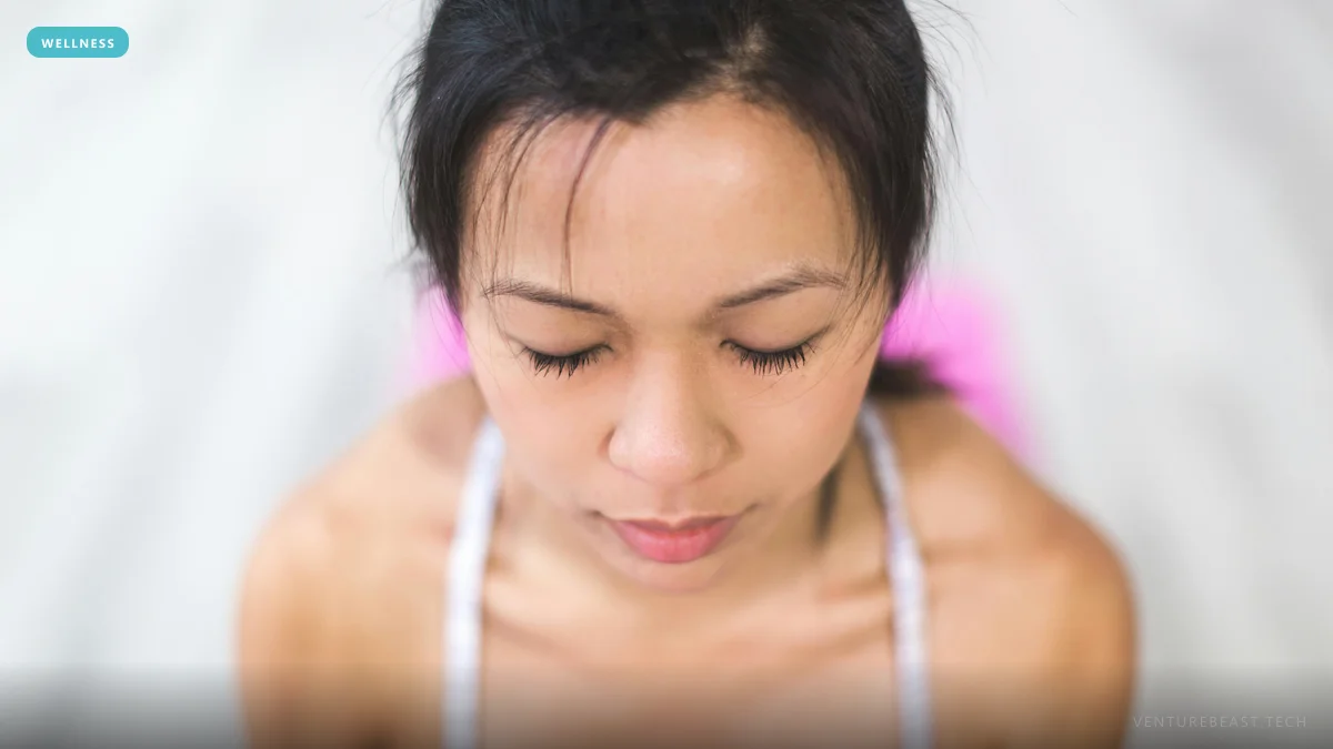 Woman with eyes closed and head bowed, calmly meditating, seen from above