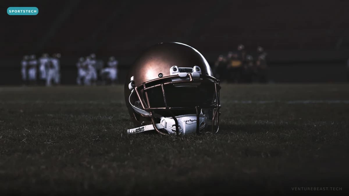 A football helmet resting on the turf of a dark field at night, with players blurred in the distance
