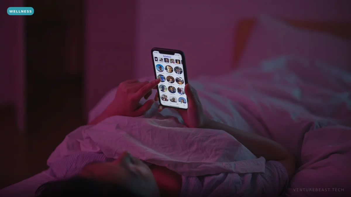 A person lying in bed at night holding up a glowing smartphone full of app icons