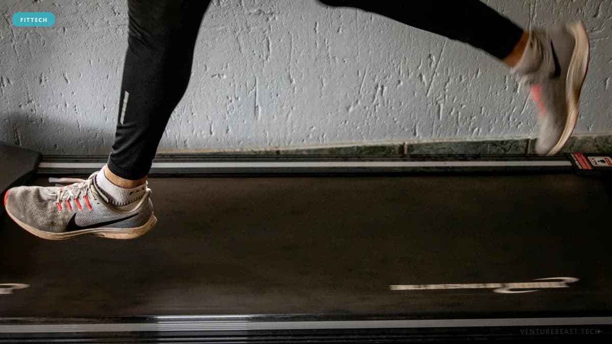 Close-up of a runner's legs in black tights and gray Nike sneakers mid-stride on a treadmill